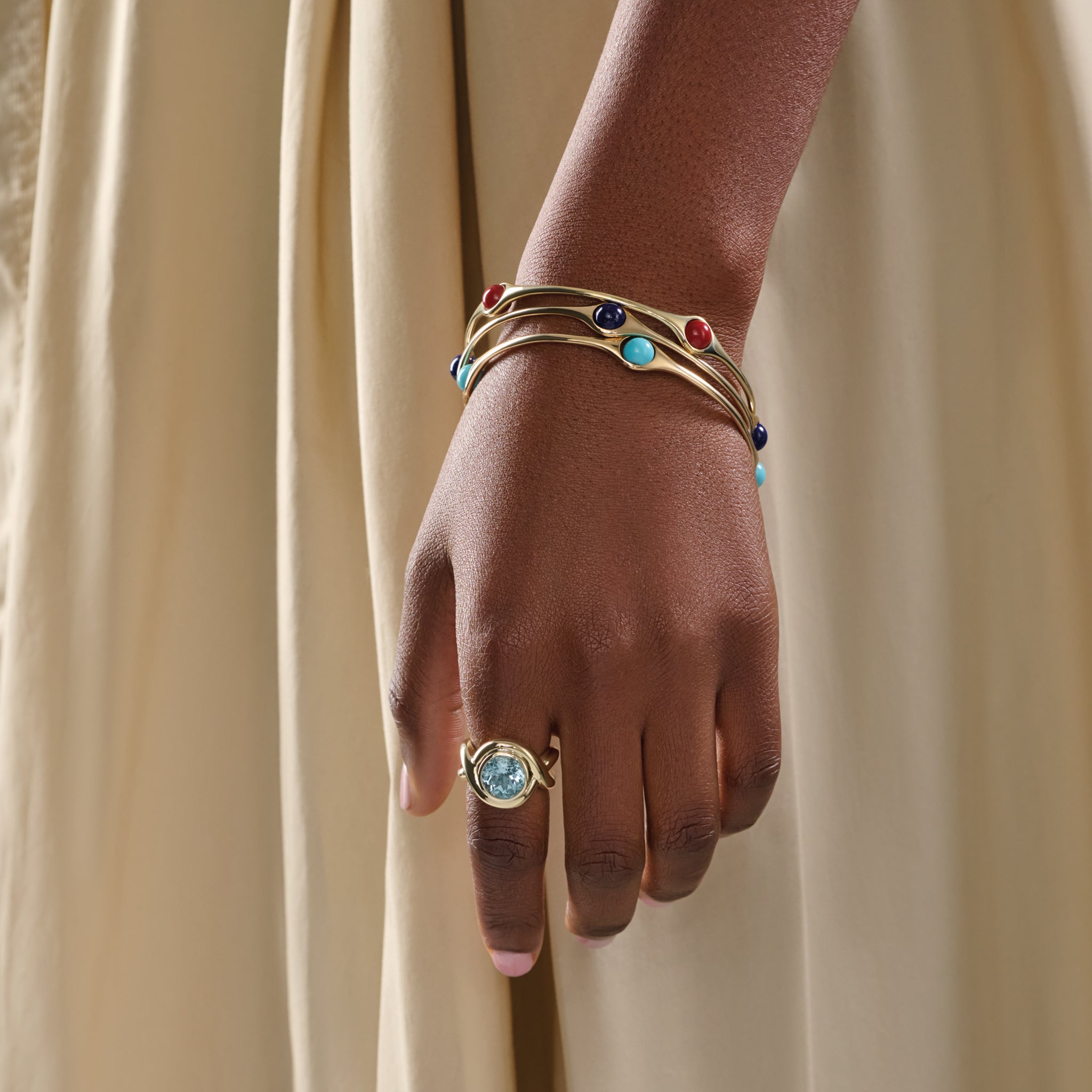 Model wearing three handcrafted yellow gold bangles featuring four beads.