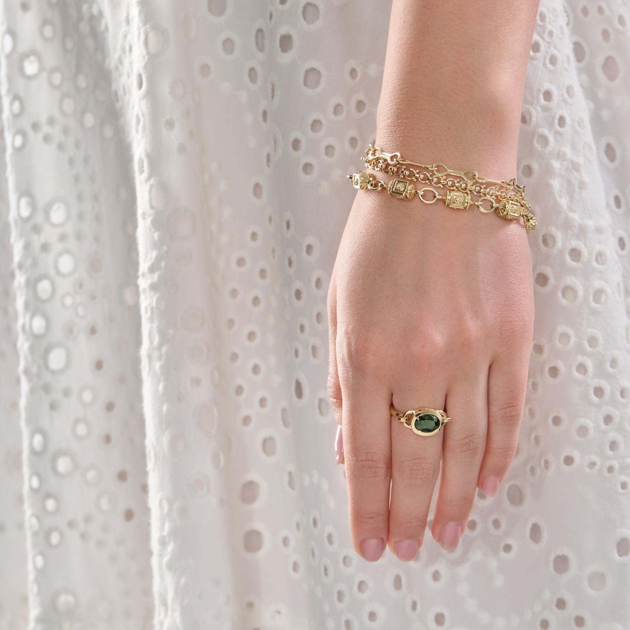 Model wearing a handcrafted yellow gold bracelet with links and small beads.