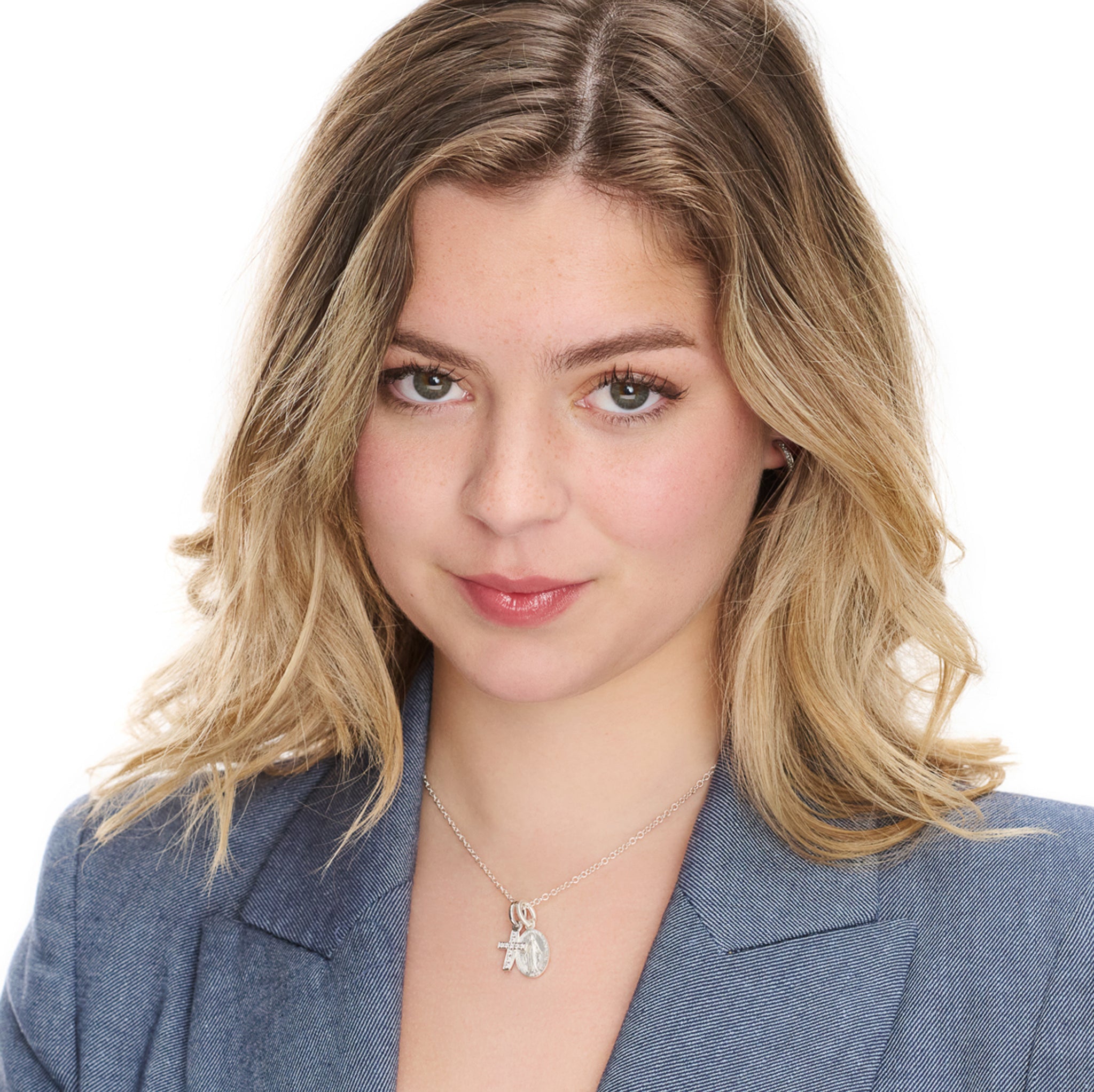 Model wearing a handcrafted Aeternitas Etoile white gold cross necklace pendant set with diamonds, birthstone of April, hanging from a necklace chain.