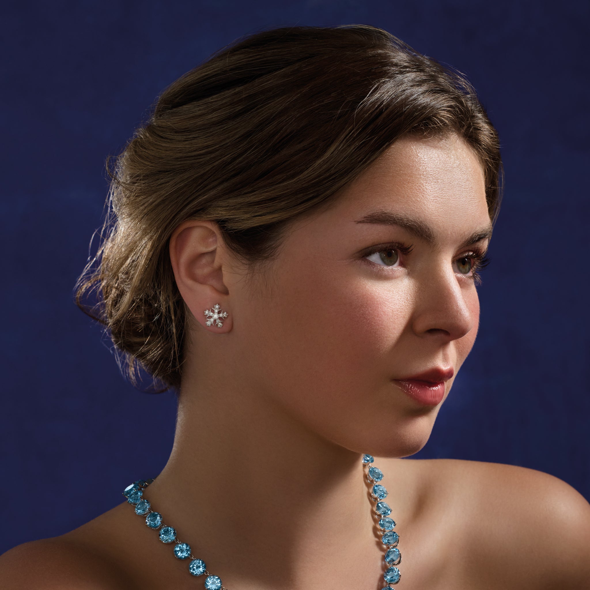 Model wearing handcrafted 18ct white gold snowflake shaped earrings with diamonds.
