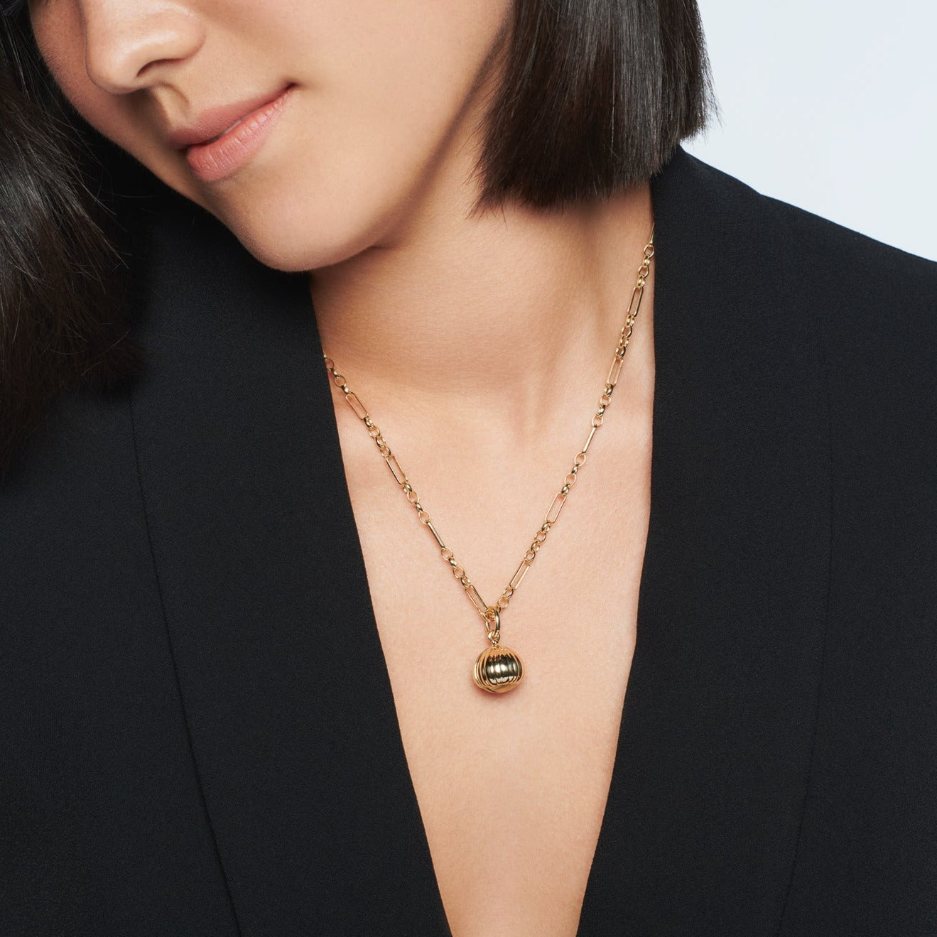 Model wearing a handcrafted necklace pendant with a hazelnut design in precious metal.