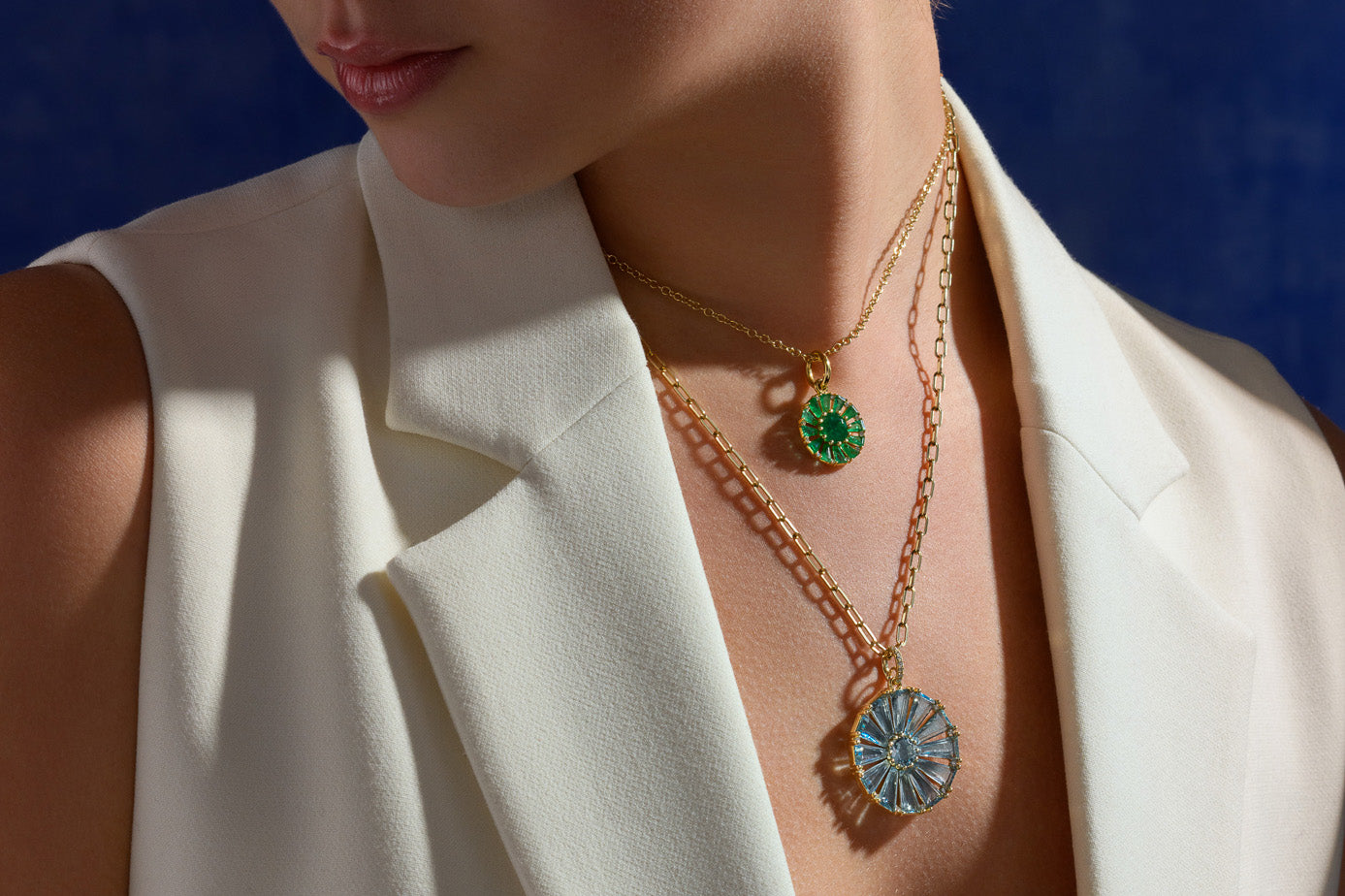 Model wearing handcrafted yellow gold necklace pendants featuring a circular shape with baguette cut precious gemstones with a central facetted gemstone, the Roi Soleil design.