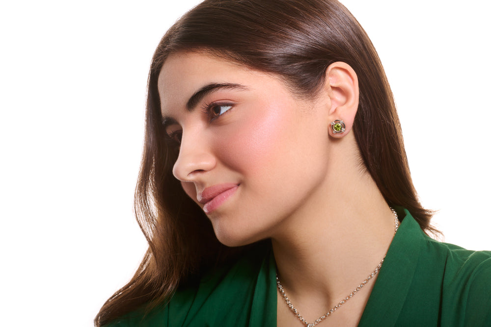 Model wearing handcrafted white gold earring halos with diamonds and peridot stud earrings at the centre, birthstone of August.