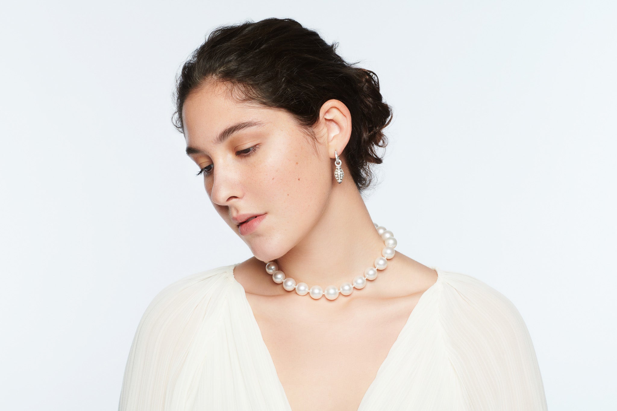 Model wearing a handcrafted pearl necklace with white gold pearl and diamond earring drops.