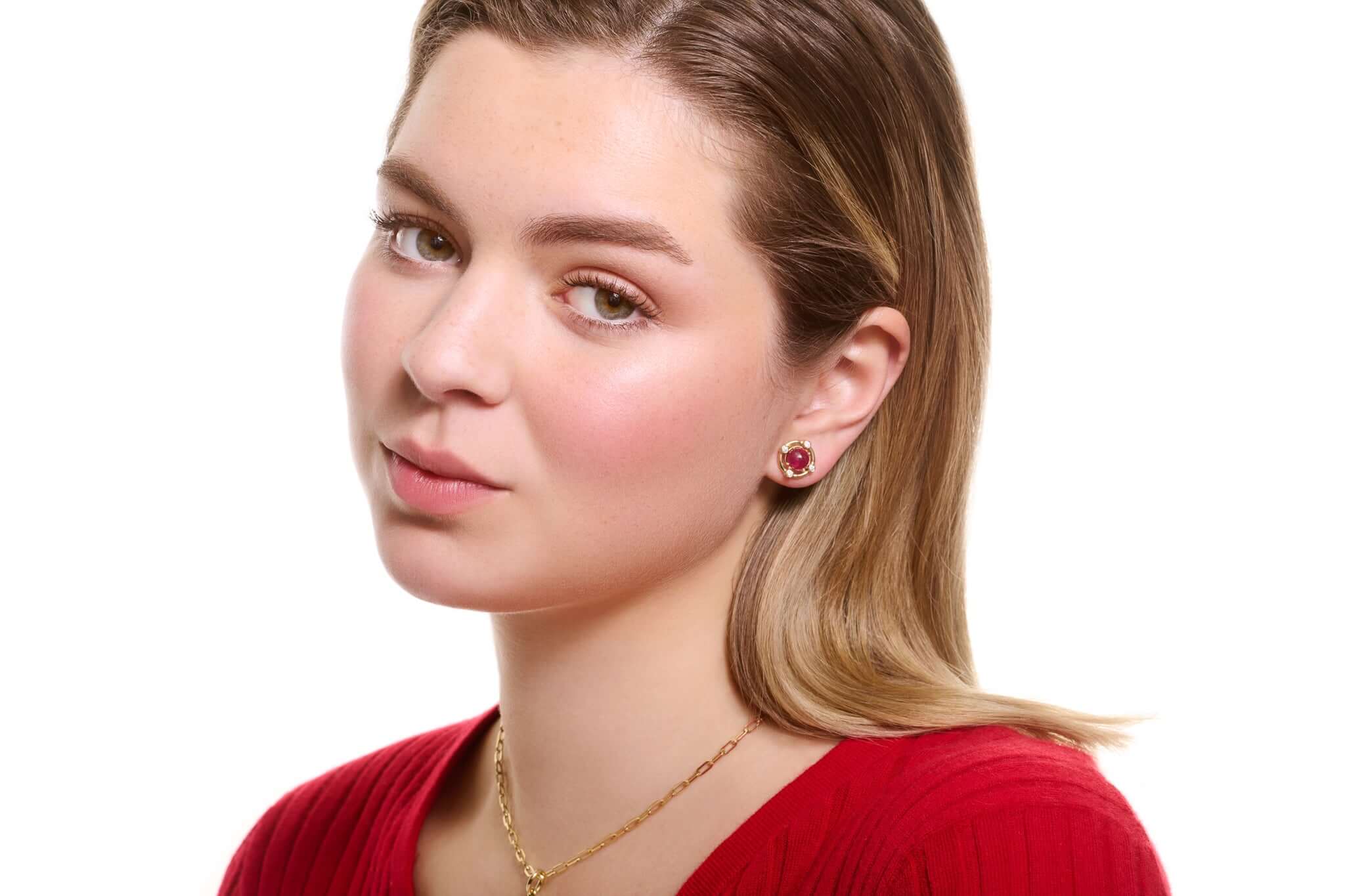 Model wearing handcrafted yellow gold earring halos with diamonds and ruby stud earrings at the centre, birthstone of July.