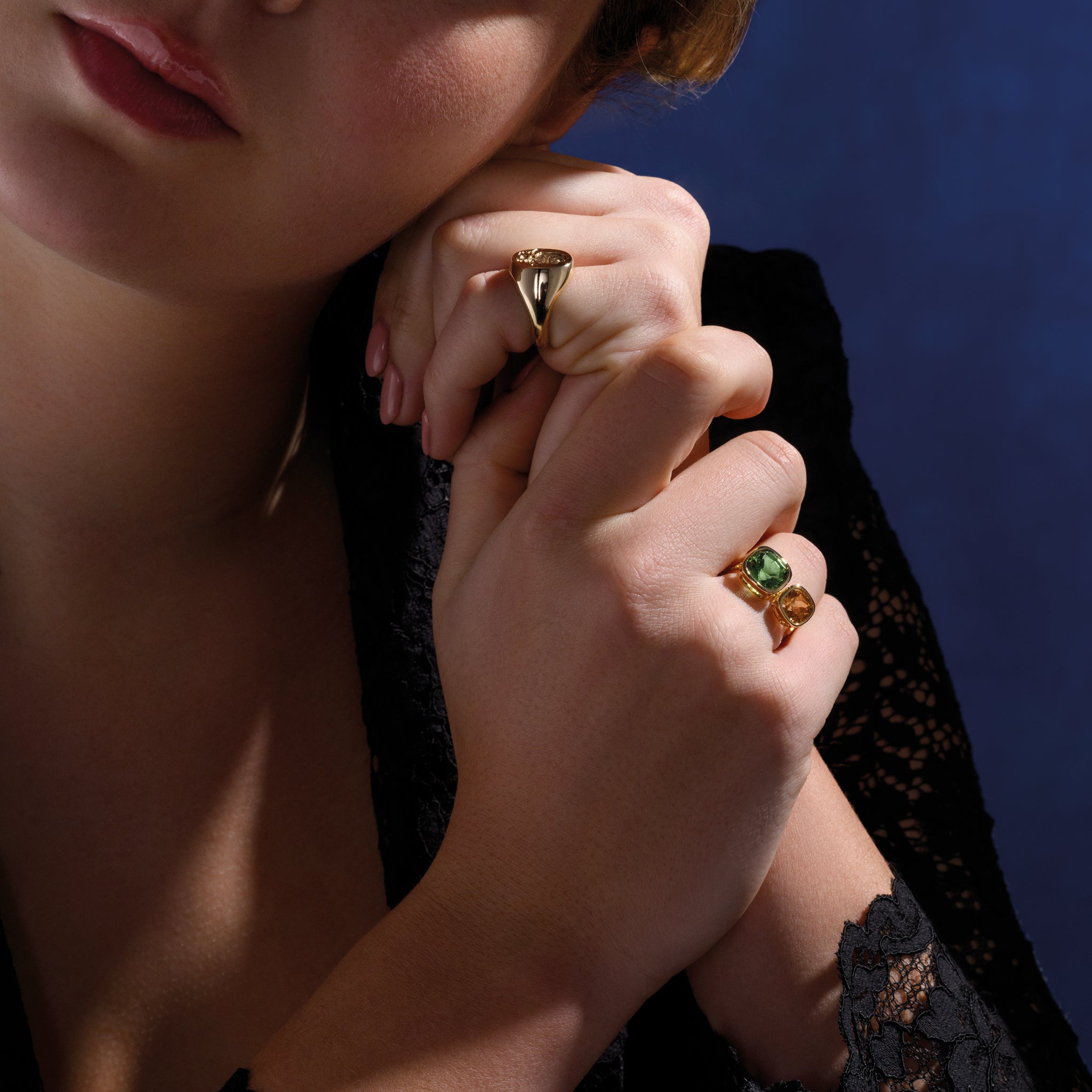 Model wearing a handcrafted 18ct yellow gold engagement ring featuring a square-cut mint tourmaline on the left and a square-cut zircon on the right.