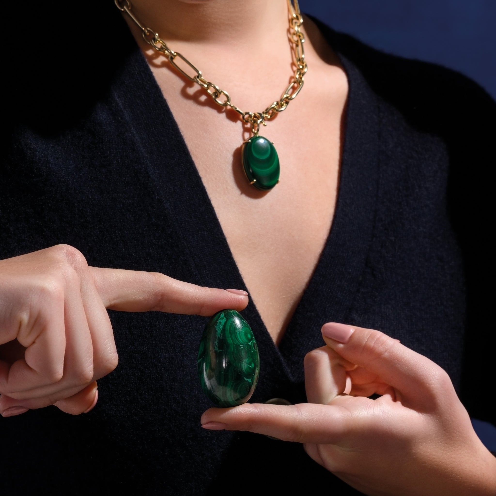 Model holding a handcrafted gemstone egg in the precious stone malachite. 