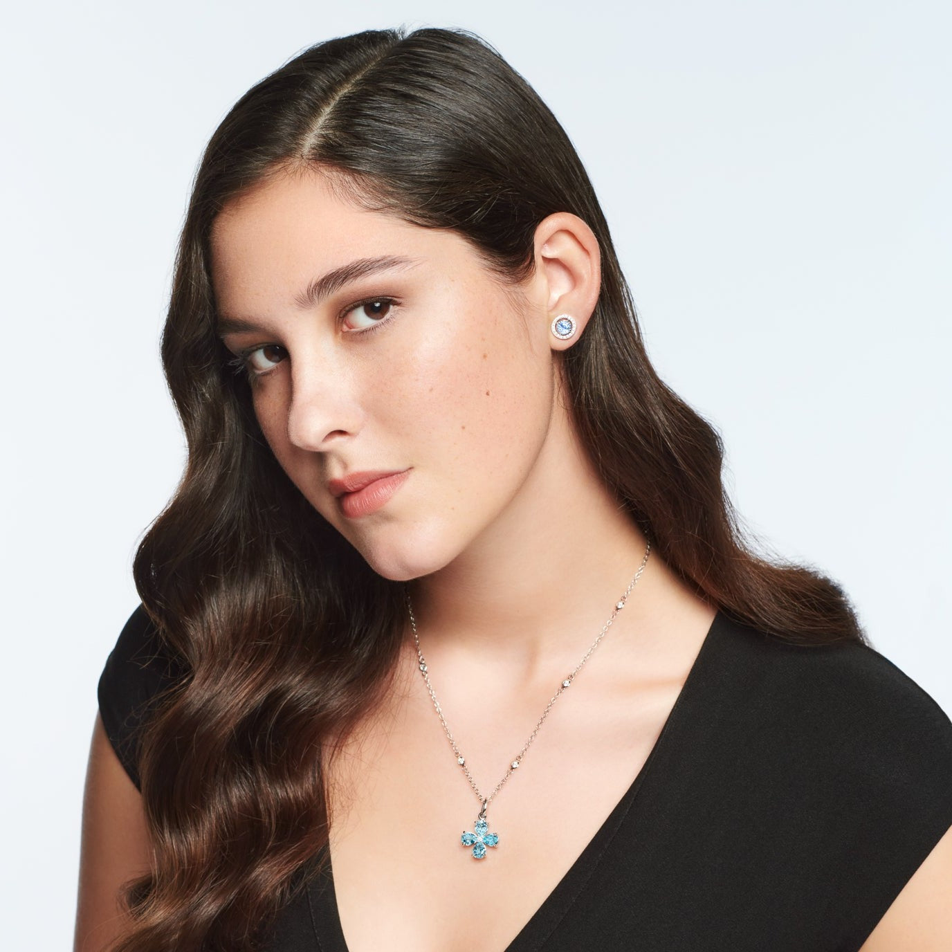 Model wearing a handcrafted white gold four-leaf clover necklace pendant with blue topaz and diamond, birthstone of November.