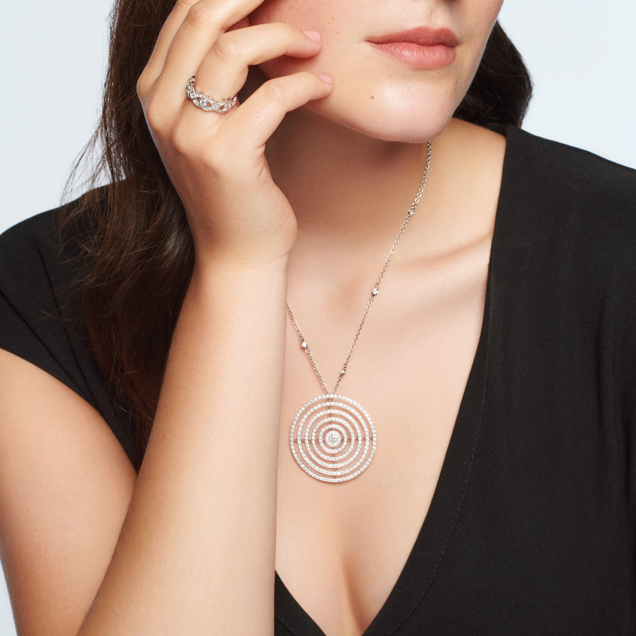 Model wearing a handcrafted 18ct white gold necklace pendant featuring five rows of circles with diamonds.