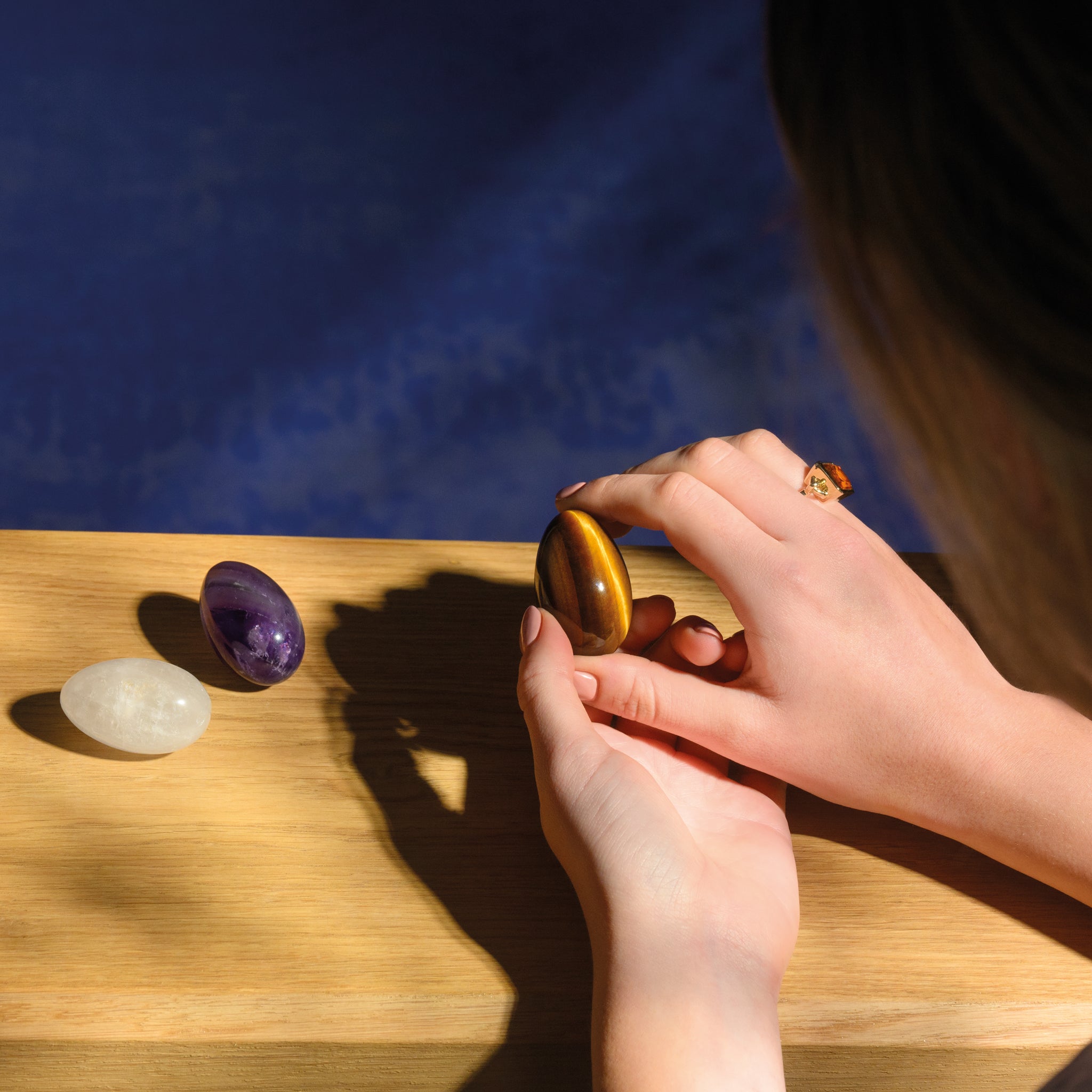 Model holding a handcrafted gemstone egg in the precious stone tiger's eye. 