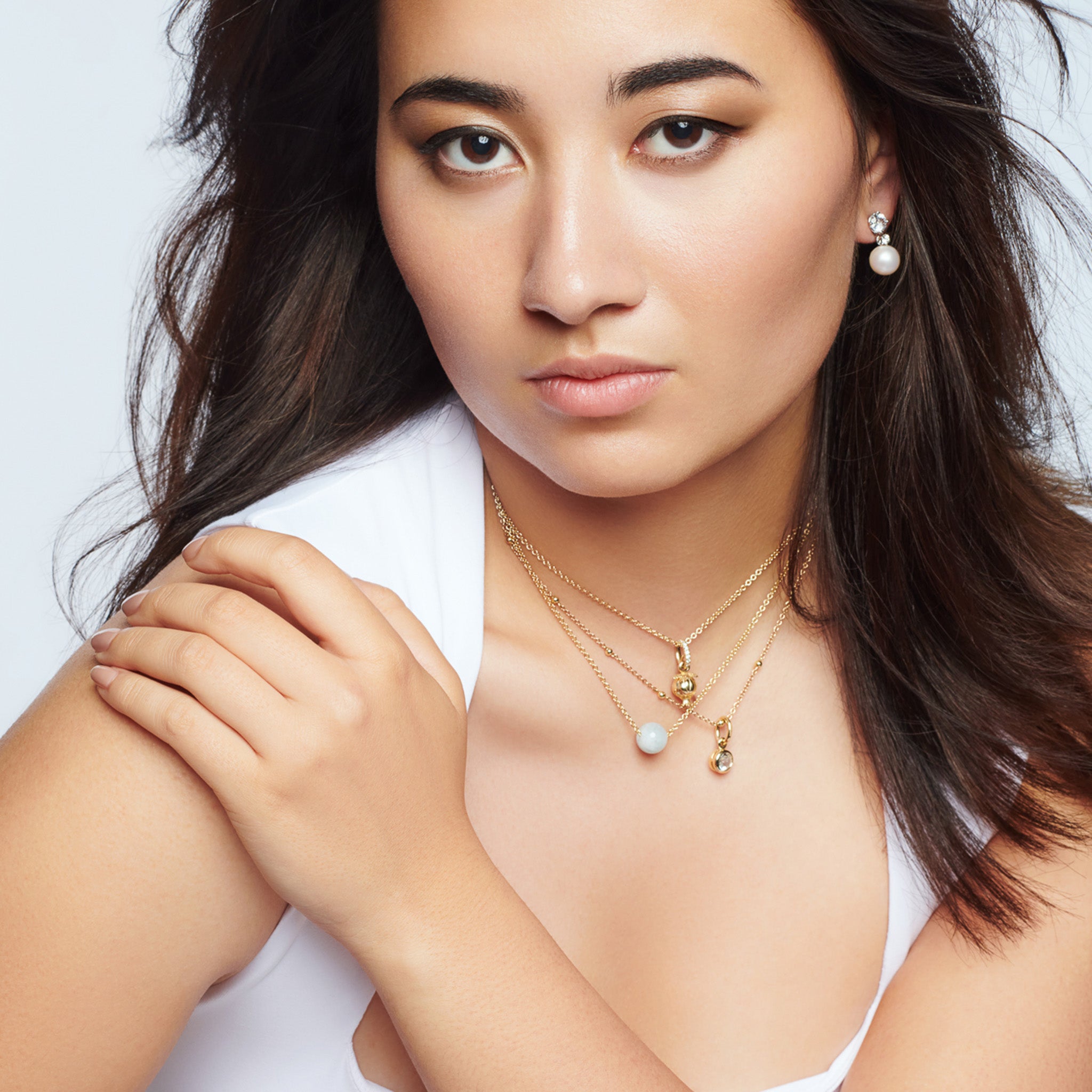 Model wearing a handcrafted necklace pendant in precious metal featuring a round precious stone.