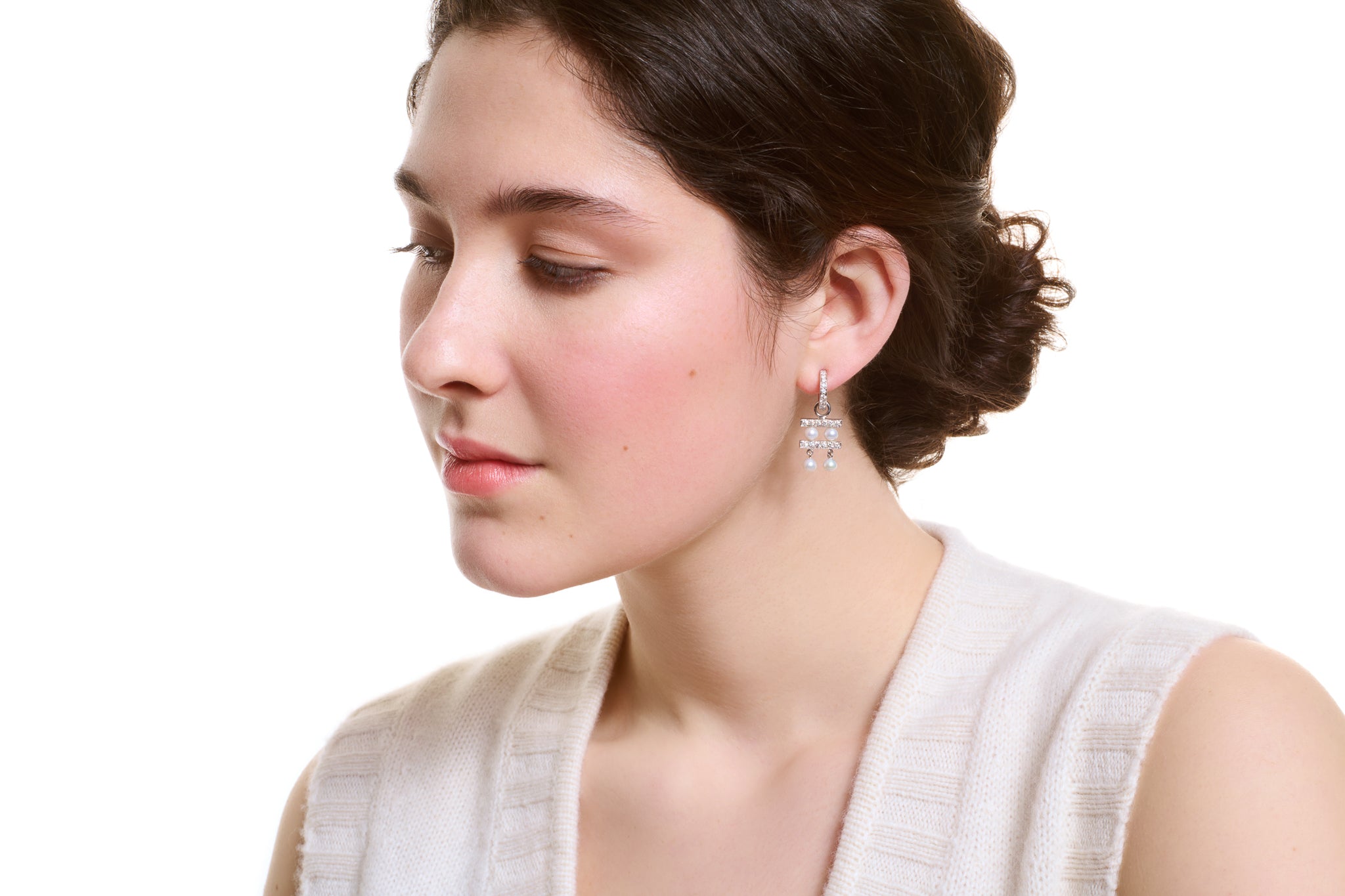 Model wearing handcrafted white gold earring drops with diamonds and pearls, birthstone of June.