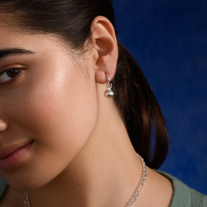 Model wearing handcrafted sterling silver earring drops with a hazelnut design. 