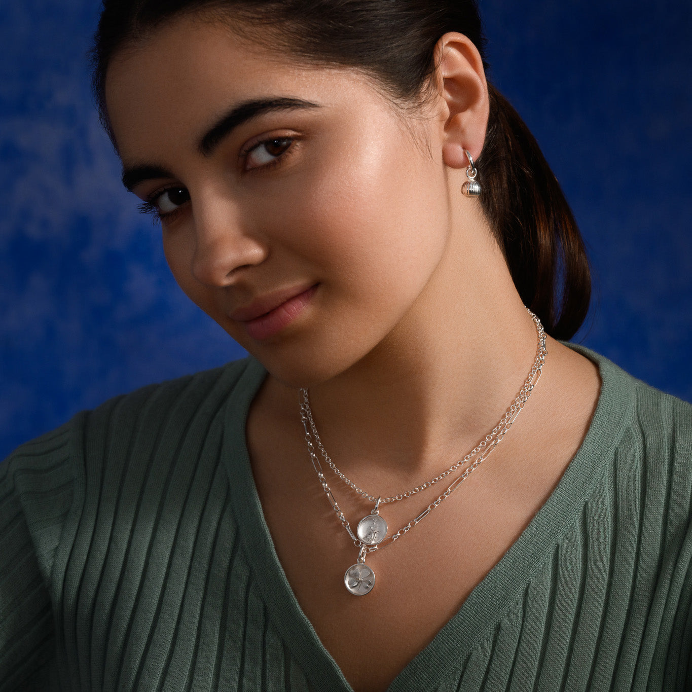 Model wearing a handcrafted sterling silver necklace pendant 'en relief' with a shamrock.
