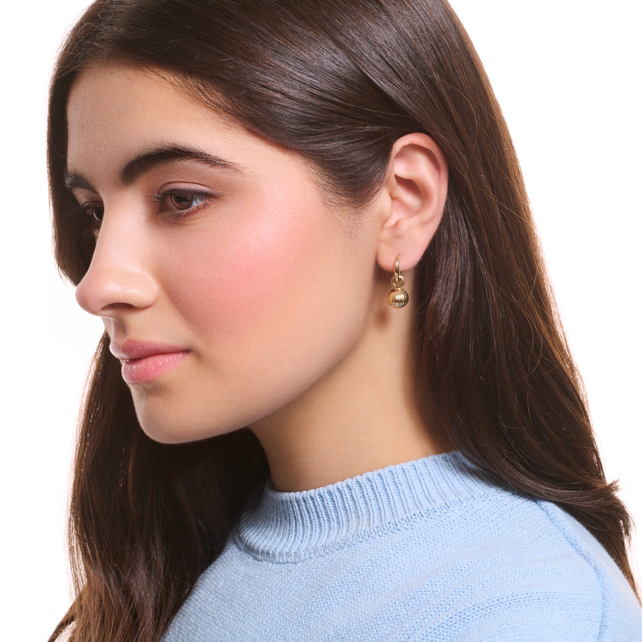 Model wearing handcrafted yellow gold earring drops with a hazelnut design. 