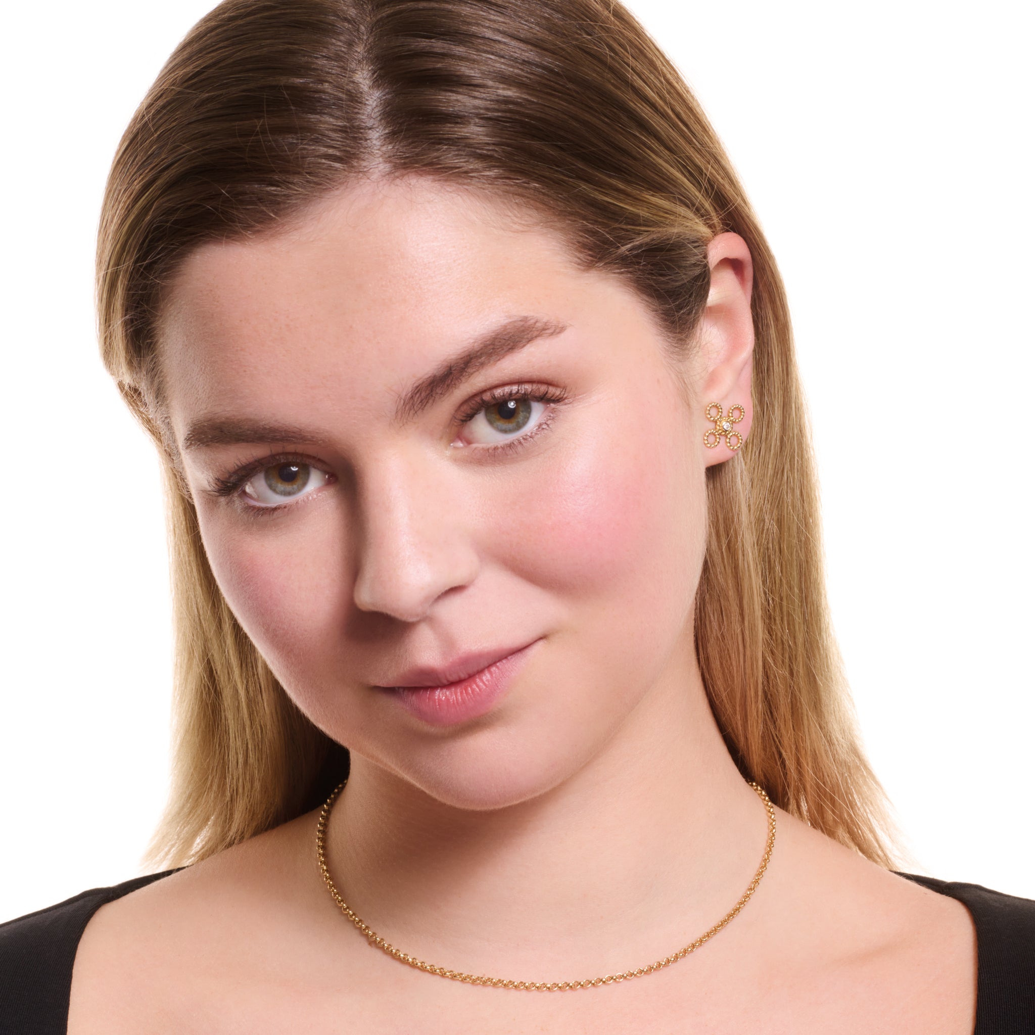 Model wearing handcrafted yellow gold stud earrings featuring a textured rope-like shape with a diamond.
