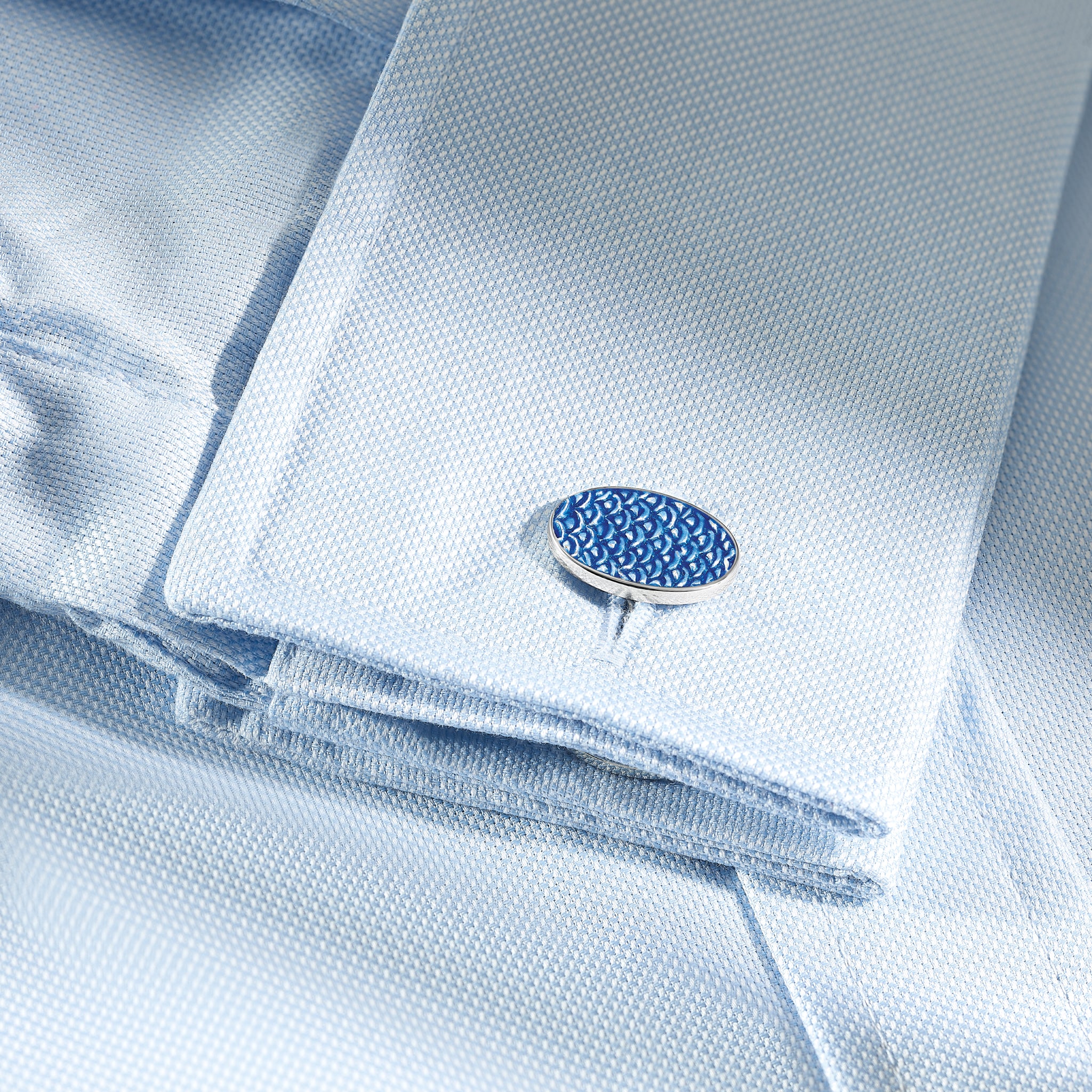 Handcrafted sterling silver double ended cufflinks featuring a wave pattern with blue enamel on a shirt.
