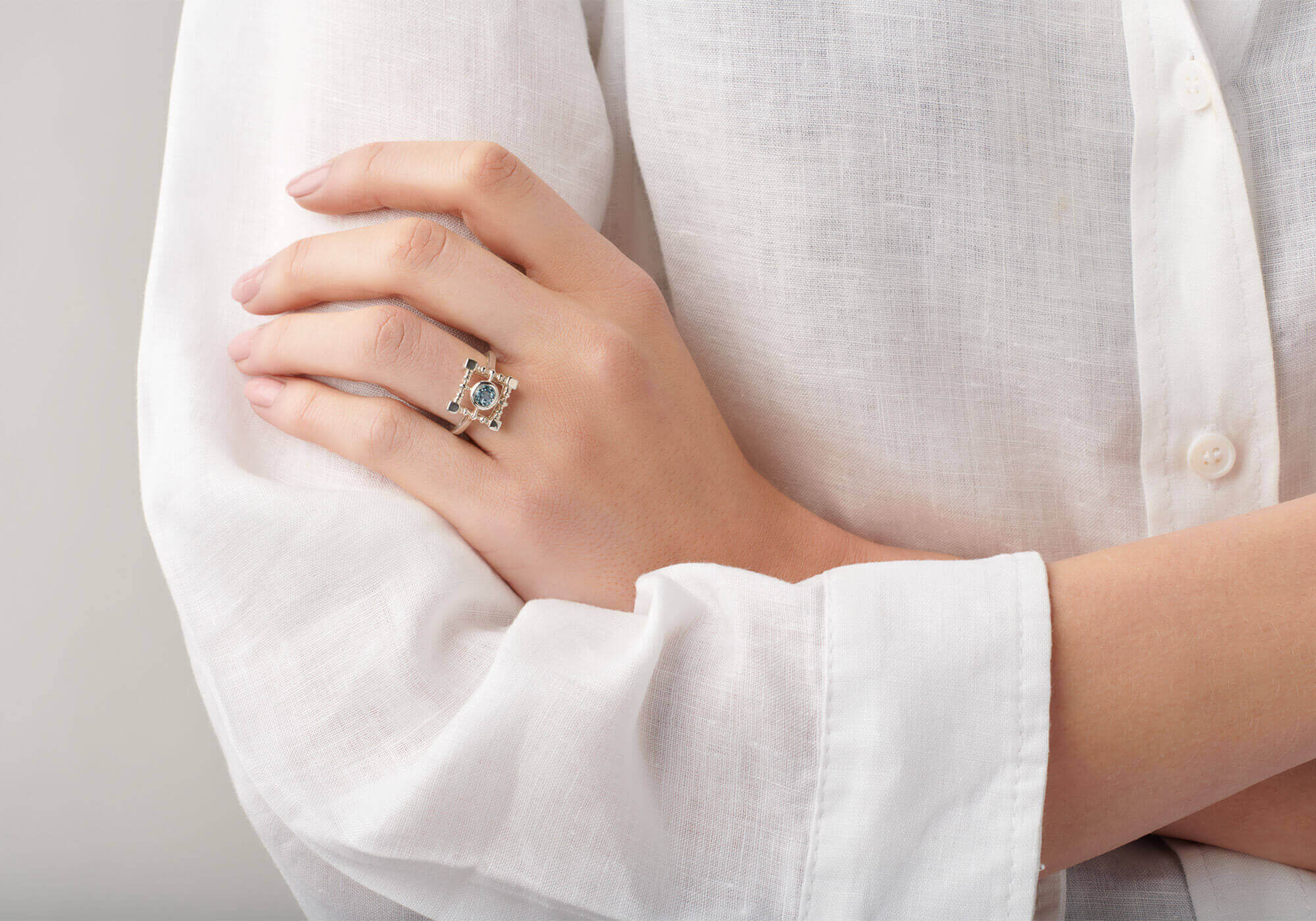 A hand wearing an 18ct white gold ring set with a vibrant blue topaz.