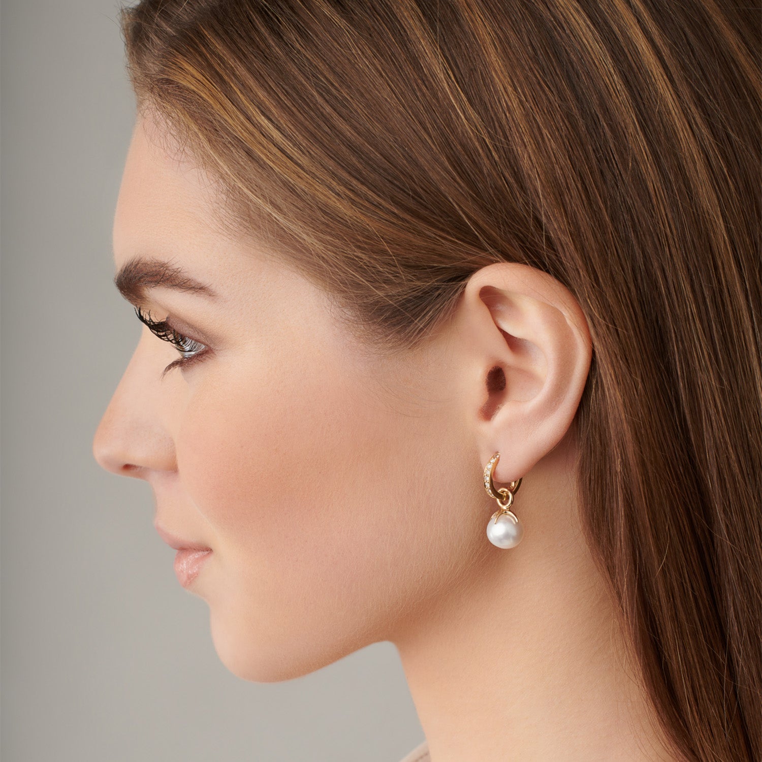 Model wearing handcrafted yellow gold earring drops with round pearls.