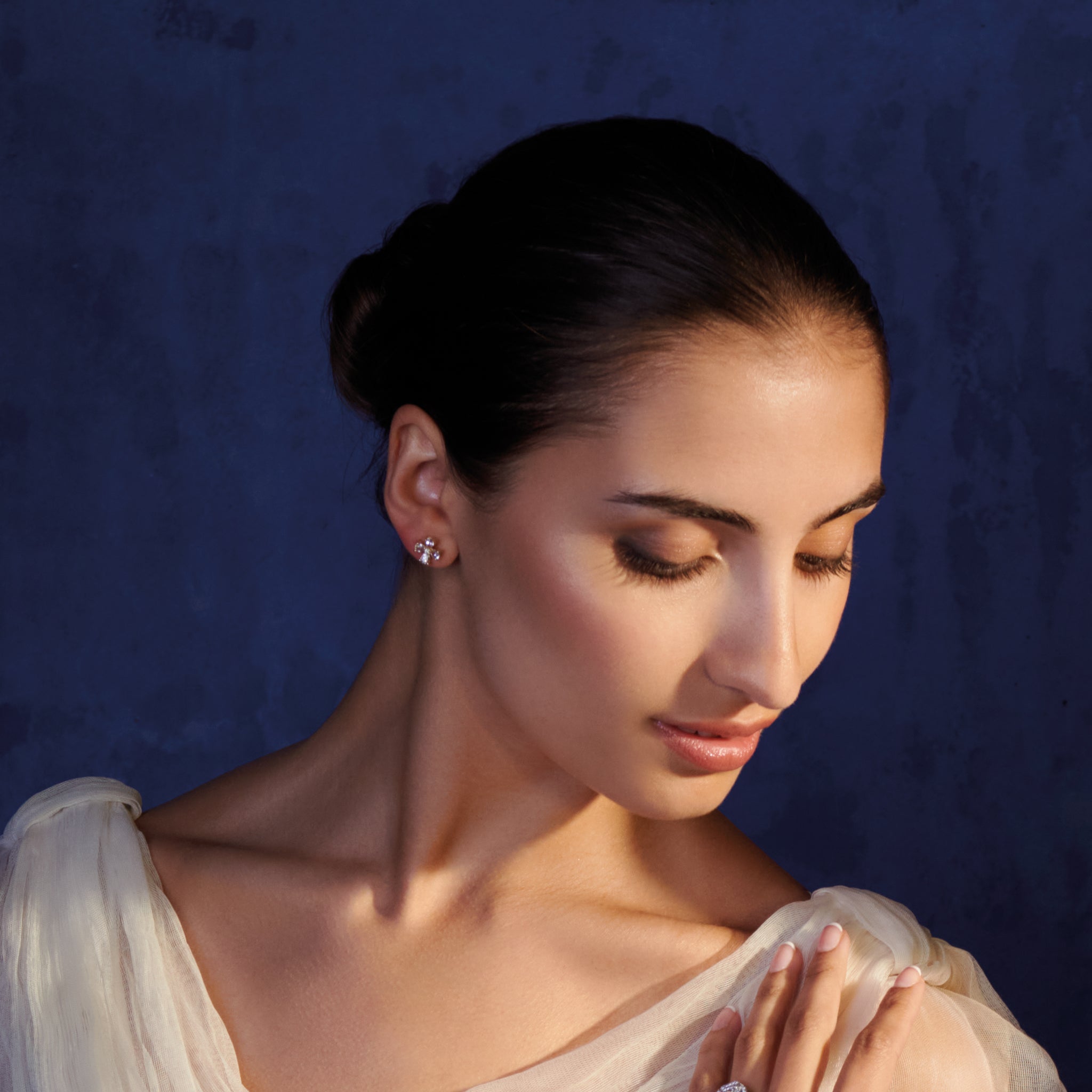 Model wearing handcrafted four-leaf clover earring studs in precious metal with precious stones.