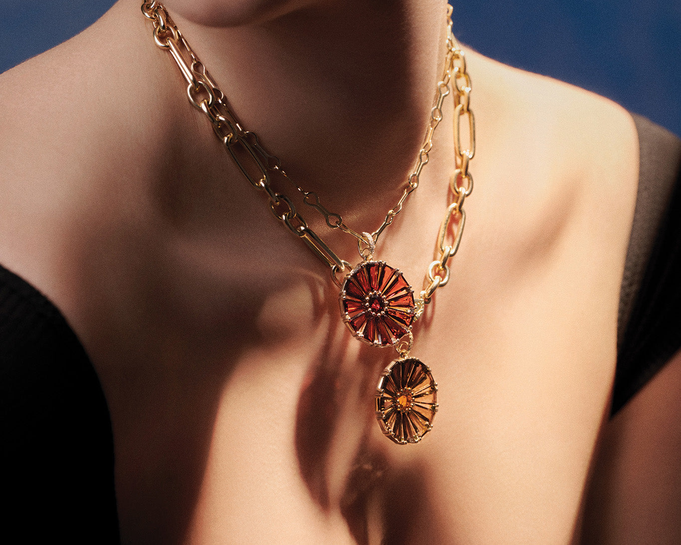 Model wearing handcrafted yellow gold necklace pendants featuring precious gemstones of garnet and smoky quartz, colours of autumn.