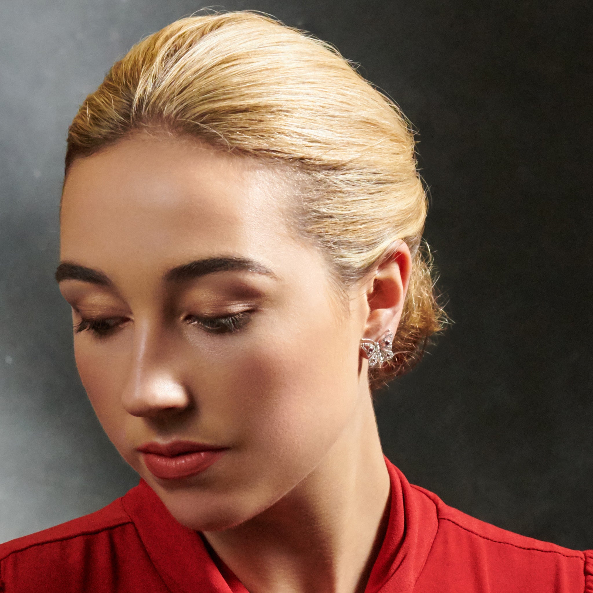 Model wearing handcrafted 18ct white gold butterfly shaped earrings with rubies and diamonds. 