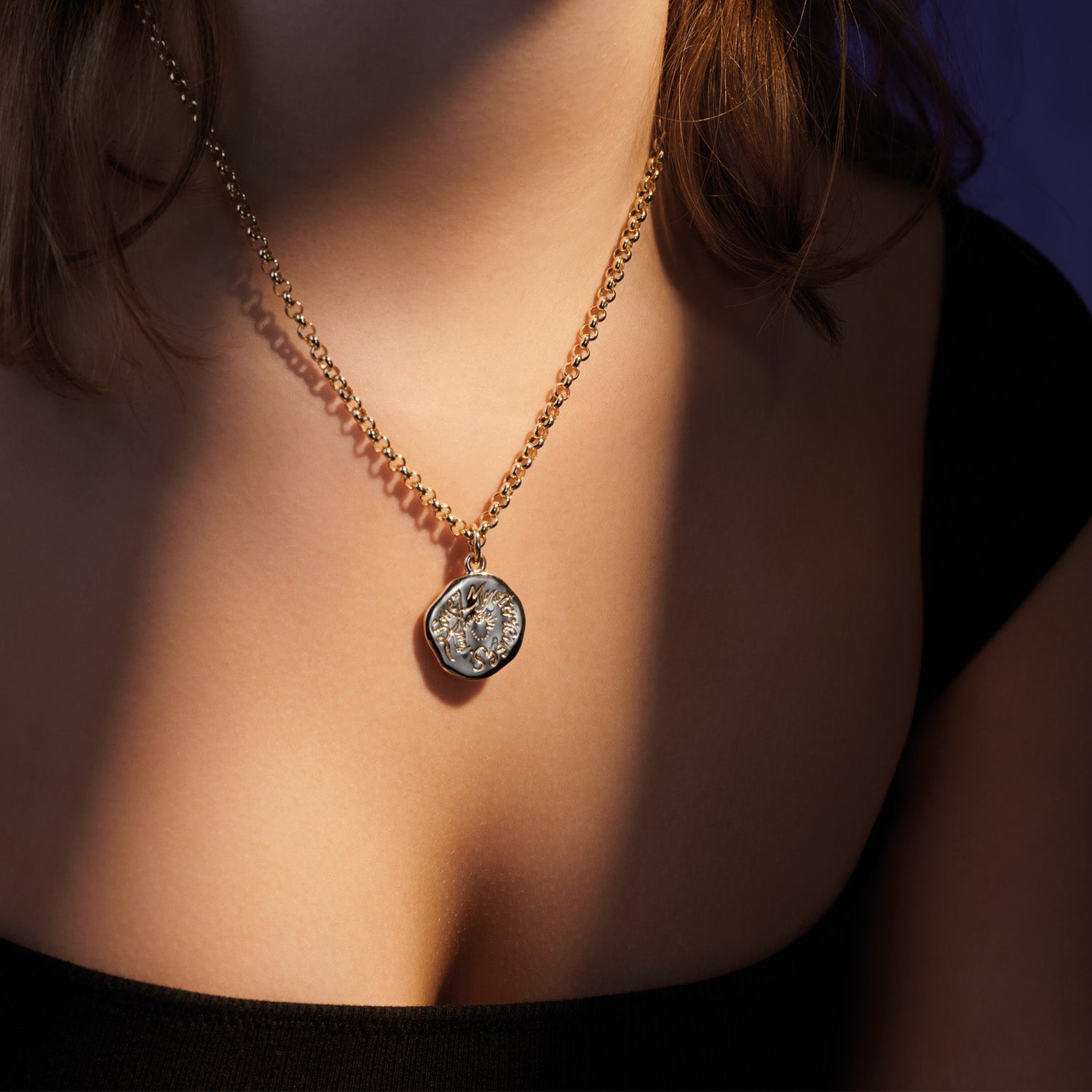 Model wearing a handcrafted yellow gold necklace pendant engraved with a quote.