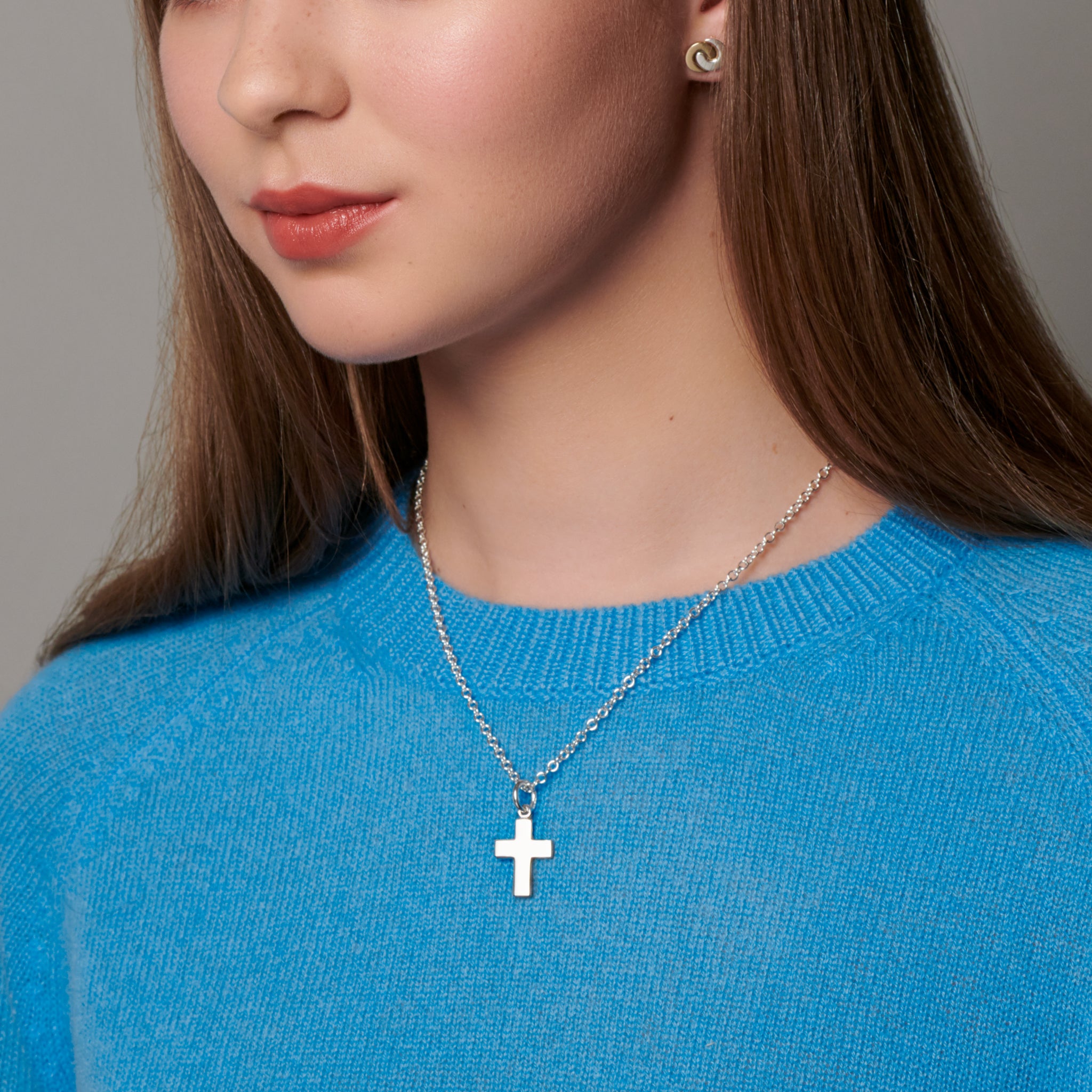 Model wearing a handcrafted round sterling silver cross necklace pendant on a sterling silver chain.