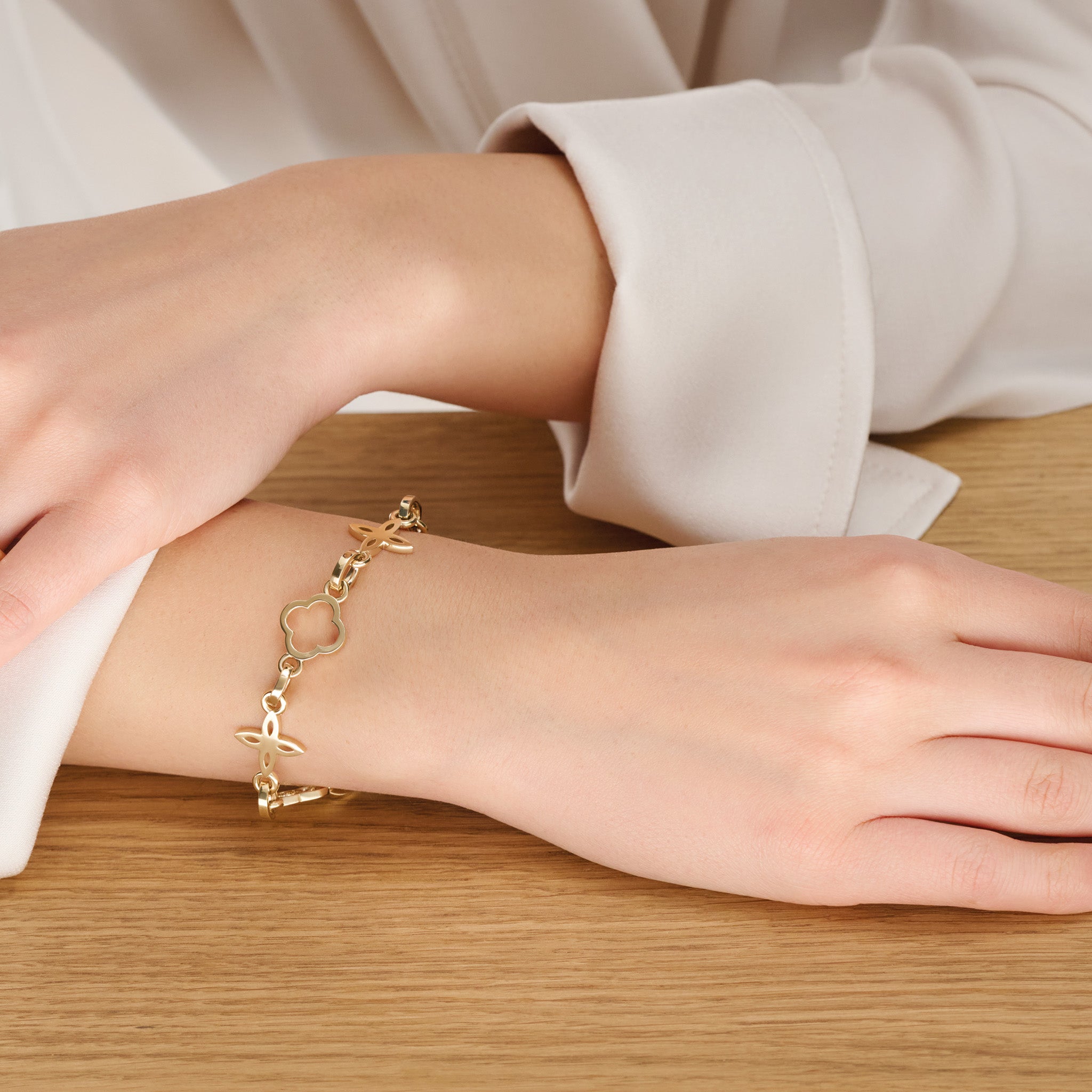 Model wearing a handcrafted yellow gold bracelet with star-shaped links.
