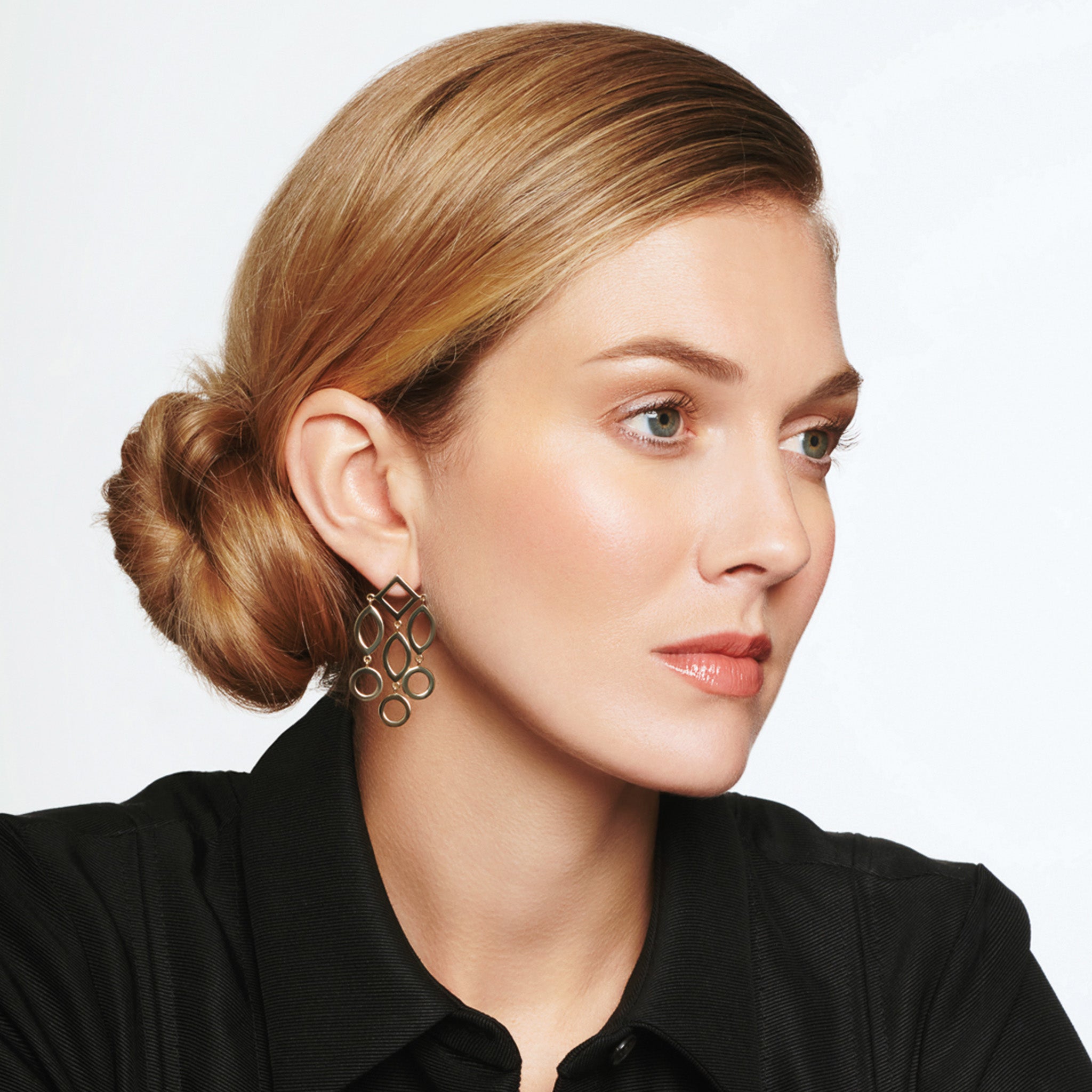 Model wearing handcrafted yellow gold earrings featuring circular and oval shapes.
