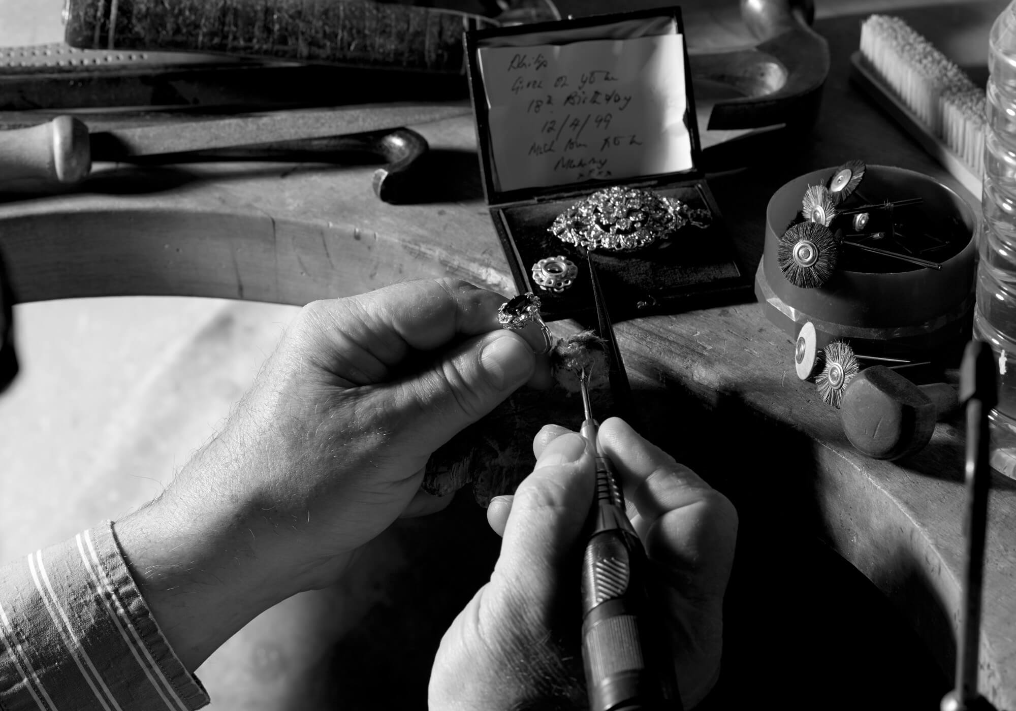 Craftsman polishing an engagement ring created from an heirloom brooch in London workshop.